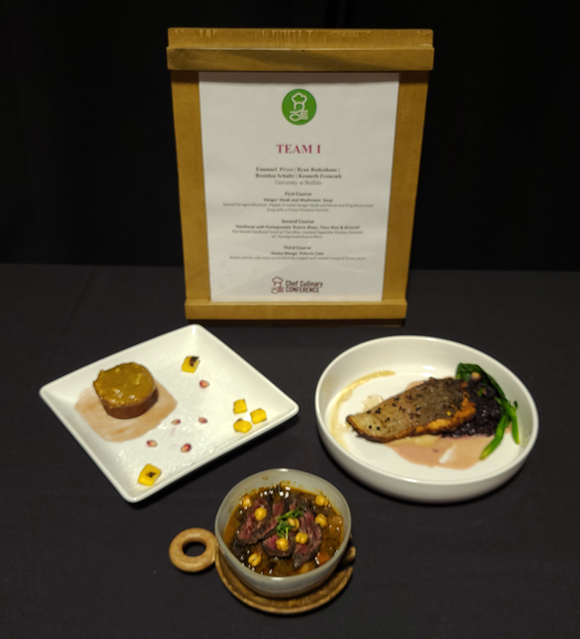 The plated three course meal with the description on a plaque behind the dishes.