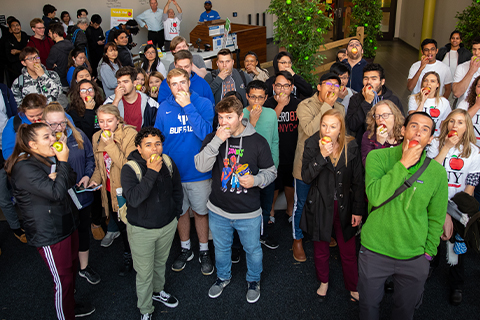 Students and staff biting into apples for the Apple Event at Crossroads Culinary Center on North Campus.