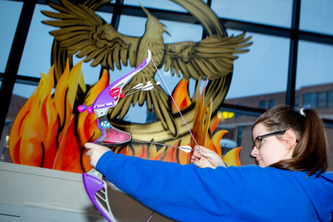 Student using toy bow and arrow at the Hunger Games Event in Crossroads Culinary Center on North Campus.
