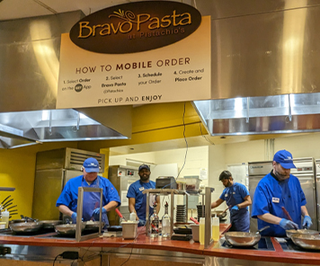 Associates making pasta dishes under the Bravo Pasta logo awning