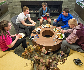 Students enjoying a meal together near the fireplace