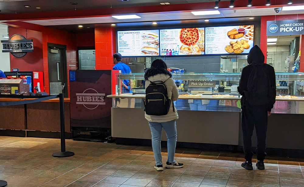 Hubies order and pickup area, featuring the digital sign menuboards behind the counter