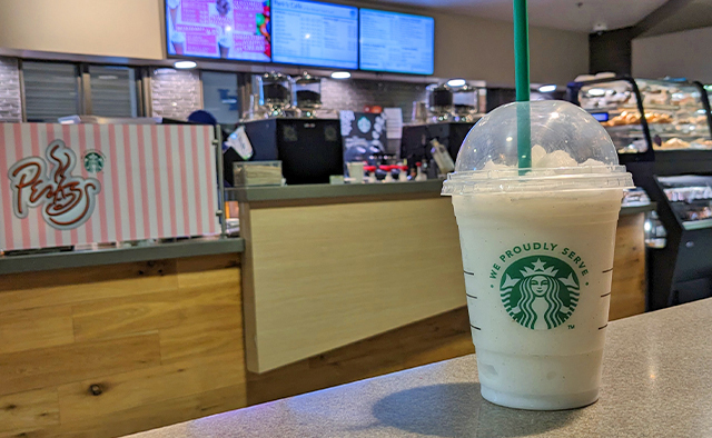 A vanilla bean frappe overlooking the Perks ordering counter and digital menuboards