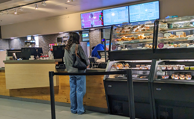 Student ordering from the Perks counter overlooking the digital menuboards
