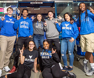 Students posed wearing University at Buffalo apparel in front of the Campus Tees store