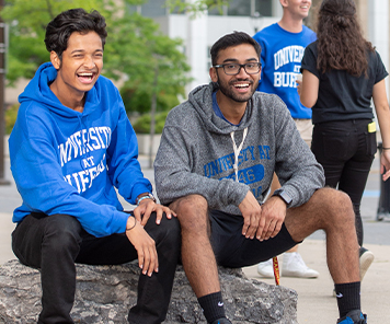 Students posed wearing University at Buffalo apparel outside in front of the Center for the Arts