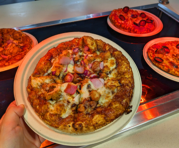 Personal size BBQ chicken pizza alongside personal size cheese and pepperoni pizzas at Piza Pizza