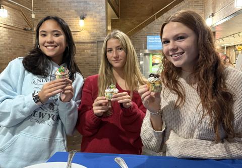 Three students showing their decorated cupcakes