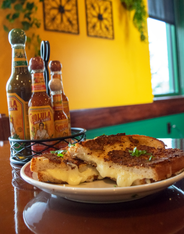 Cotija Grilled Cheese with hot sauce bottles behind