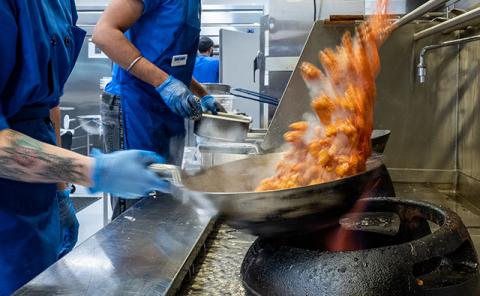 Associate cooking seafood on a large stove at Crossroads Culinary Center