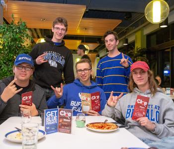 Students showing their UB Bulls pride and posing with the Clue pamphlets and their special dinners
