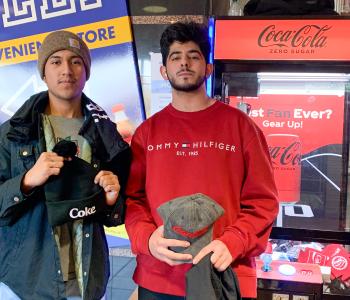 Two male students with their prizes from the Coke claw machine