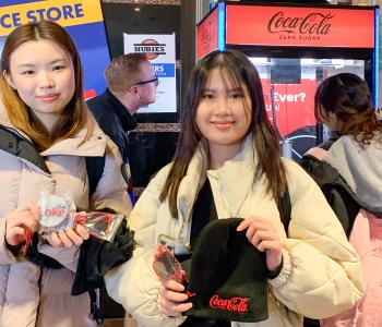 Two female students with their prizes from the Coke claw machine
