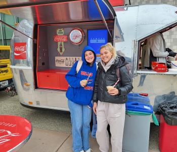 Two students with their Coca Cola floats outside of the Coca Cola Throwback car