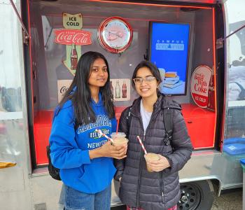 Two students with their Coca Cola floats outside of the Coca Cola Throwback car