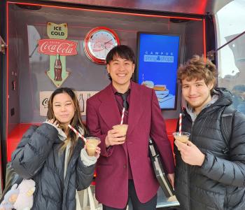 Three students with their Coca Cola floats outside of the Coca Cola Throwback car