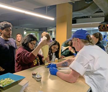 A chef helping students decorate cupcakes