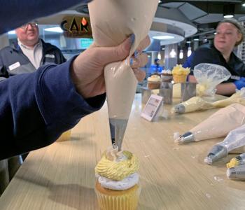 Someone placing icing on top of a cupcake