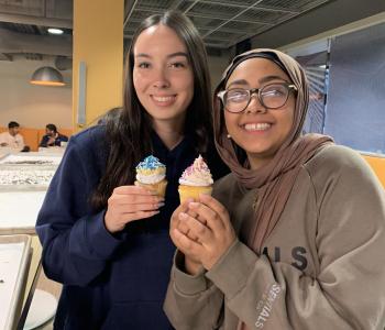 Two students smiling and showing their decorated cupcakes