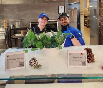 Two chefs at the Governors Dining Center smiling and giving thumbs up in front of holiday decor