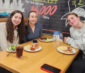 Three students eating pizza together at Governors Dining Center