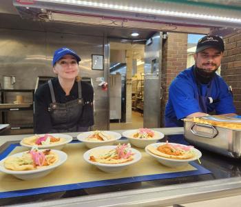 Two chefs at the Governors Dining Center smiling as they are plating food