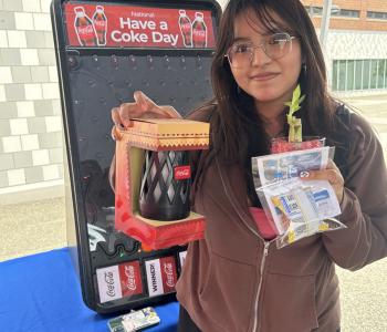 Student smiling showing off their Coca Cola prizes