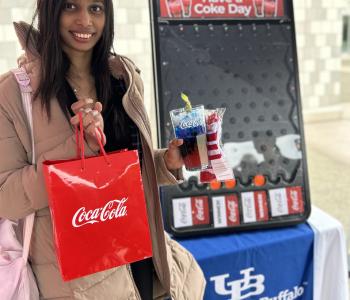 Student smiling showing off their Coca Cola can and their prize