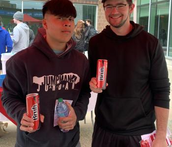 Two students showing their Coca Colas and the one is also holding his prize