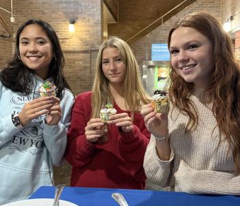 Three students showing their decorated cupcakes