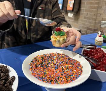 Student decorating their frosted cupcake with topings