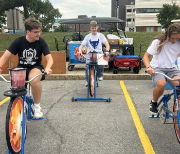 Three students riding blender bikes