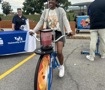 Student smiling while riding a blender bike