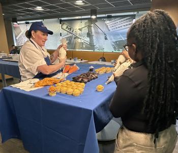 Student talking to a chef as they decorate their cupcake