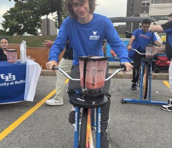 Student smiling while riding a blender bike