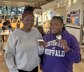 Two students showing their decorated cupcakes