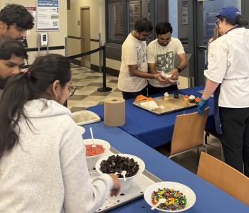 Students decorating their cupcakes, a chef helping two of them