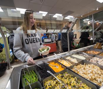 A student putting black beans in their salad bowl. Photo by Onion Studio.