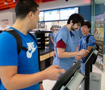 Students ordering on the Corner Café kiosks and laughing. Photo by Meredith Forrest Kulwicki.