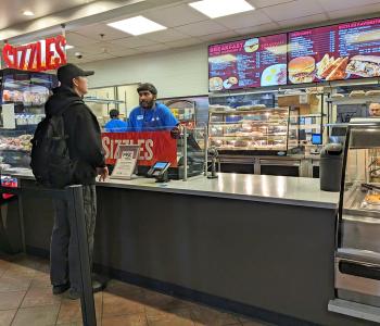 A student ordering at the Sizzles counter.