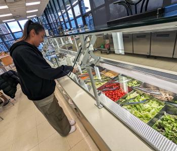 A student creating their own salad at the salad station of Goodyear Dining Center, located in the seating area.