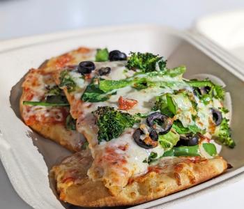 Flatbread pizza from The Cellar topped with broccoli, spinach, black olives and peppers.
