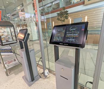 Two ordering kiosks next to the breakfast sandwich warmer. They are on the landing page where you can see categories: Breakfast, Subs, Wraps, Salads, Flatbread Pizzas and Allergens.