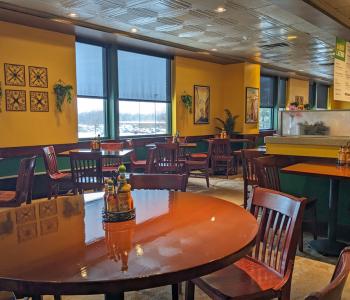 Inside Sabor Latino, featuring the yellow walls and wall decorations, and the tables with center pieces holding multiple flavors of hot sauce.