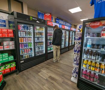 A staff member deciding what bottled beverage to get from the cooler.