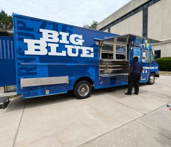 Big Blue food truck parked on South Campus. A customer is ordering food.