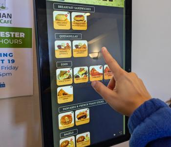 A customer making an order on the kiosk outside Harriman Café.