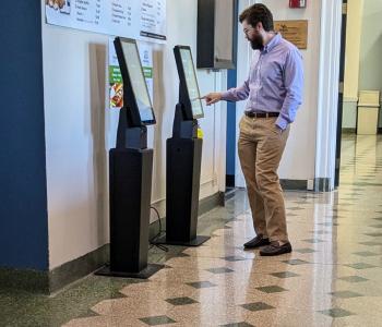 A customer ordering on the ordering kiosk outside of Harriman Café.