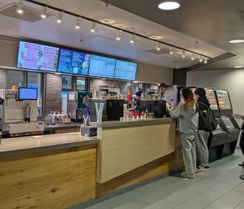 Students lining up at Perks order counter; The digital sign menuboards are behind the counter.