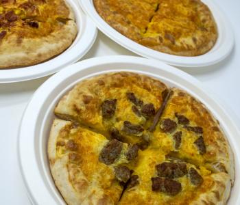 Breakfast pizzas with egg baked inside from Piza Pizza: the sausage one is in the foreground, the bacon and plain cheese ones are in the back.